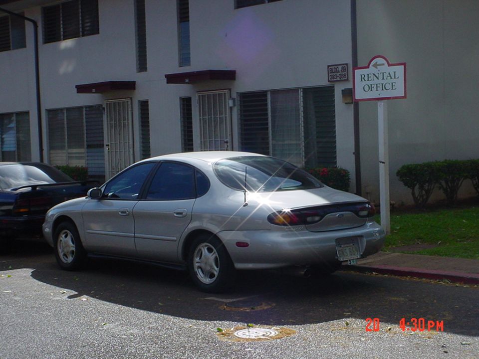 Silver Ford Taurus rear three-quarter parked near Rental Office sign and apartments