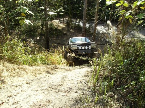 1989 Ford Bronco - This 1989 Ford Bronco navigates a challenging muddy incline on a wooded trail.