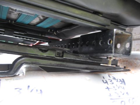 1979 Ford F-150 - The underside of a vehicle seat shows its mounting hardware and adjustment mechanism, with measurements scribbled on the floor.