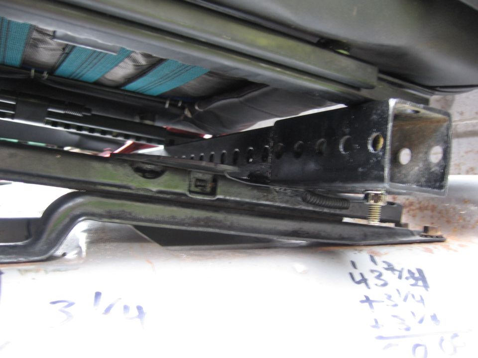Close-up of seat rails and brackets, with some handwritten measurements on the floor