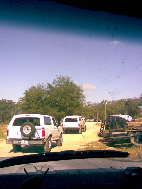 1989 Ford Bronco - Several SUVs are parked on a dirt road under a clear blue sky.