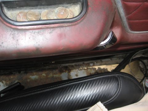 1979 Ford F-150 - Coins stored in the armrest compartment of a 1979 Ford F-150's interior door panel.