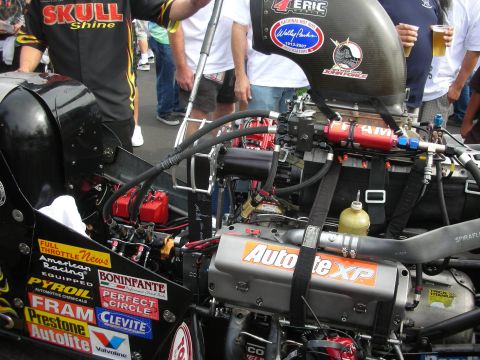 1998 Ford Crown Victoria - Close-up of a supercharged dragster engine bay covered in racing sponsor decals like Autolite, FRAM and Clevite.