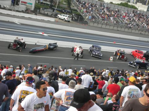 1998 Ford Crown Victoria - Vintage hot rods, a coupe and a streamliner line up on a drag strip in front of a large crowd of spectators.