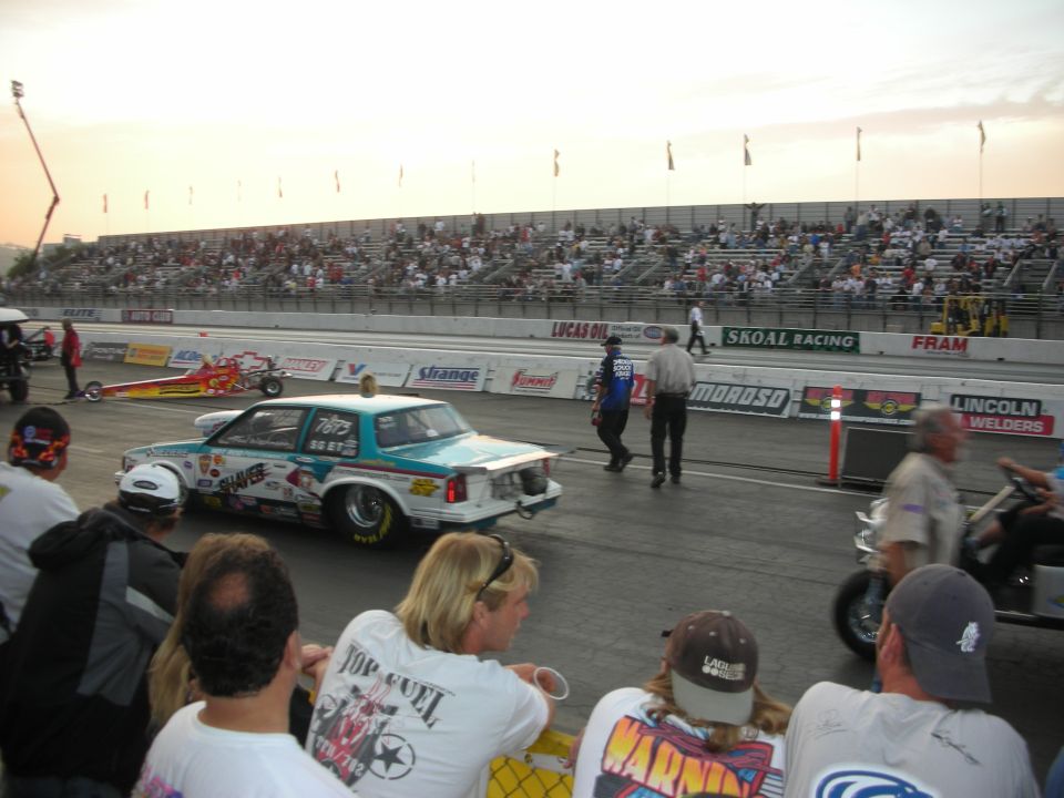Teal door-slammer drag car and a front-engine dragster staged at dusk