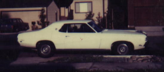 Pale yellow classic two-door coupe in side profile parked on a residential street