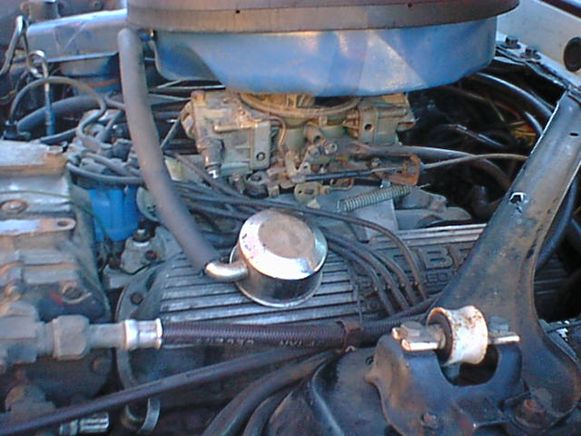 Engine bay with blue air cleaner, carburetor, chrome oil cap on finned valve cover, and wiring