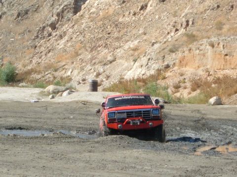 1981 Ford Bronco - This 1981 Ford Bronco navigates a muddy off-road course, displaying a website sticker on its windshield.