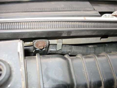 1995 Ford C-350 (Centurion Conversions) - Close-up view of a component in the engine bay, a rusted bolt and a black corrugated hose.