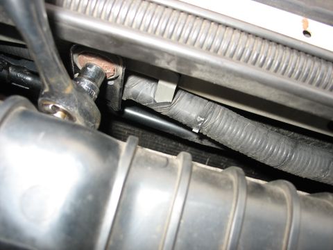 1995 Ford C-350 (Centurion Conversions) - Mechanic using a socket wrench on a bolt in the engine bay, focusing on a section of wiring.