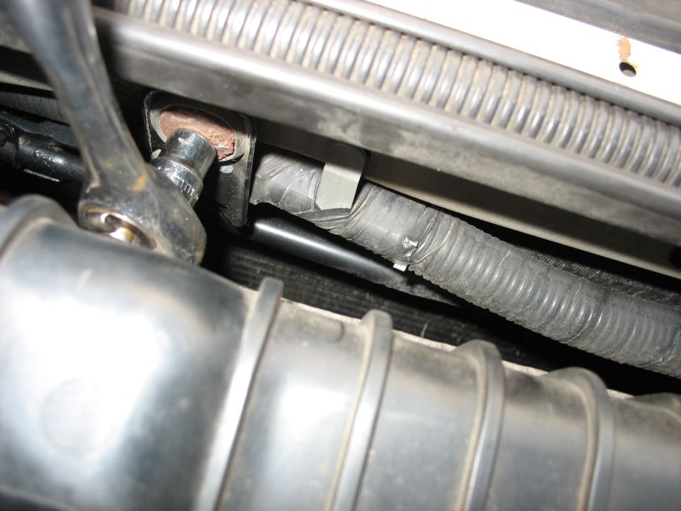 Socket wrench on bolt near engine components and wiring harness