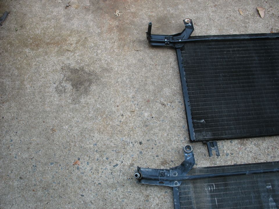 Two car AC condensers sit on a concrete surface