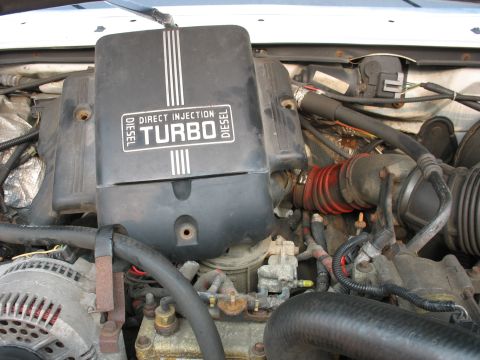 1995 Ford C-350 (Centurion Conversions) - Close-up of an engine bay, showing the turbo diesel direct injection cover and various engine parts.