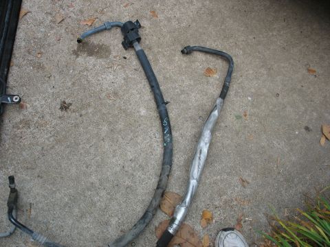 1995 Ford C-350 (Centurion Conversions) - Two AC hoses are laid out on a concrete surface, one appears to be repaired with silver tape.