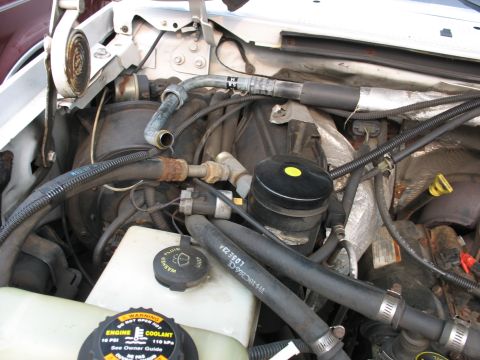 1995 Ford C-350 (Centurion Conversions) - Close-up of engine bay components, including AC system parts and coolant reservoir.