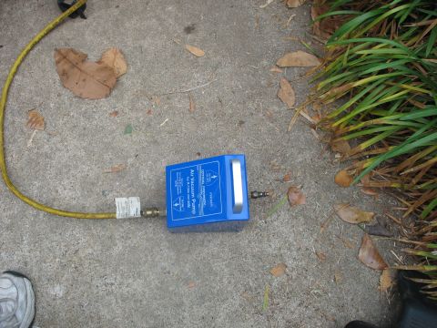 1995 Ford C-350 (Centurion Conversions) - A blue air vacuum pump with a yellow hose is shown on a concrete surface next to grass and fallen leaves.