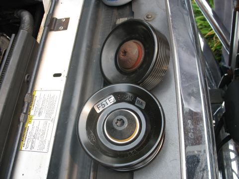 1995 Ford C-350 (Centurion Conversions) - Two idler pulleys are shown in a vehicle's engine bay, one with visible part numbers.