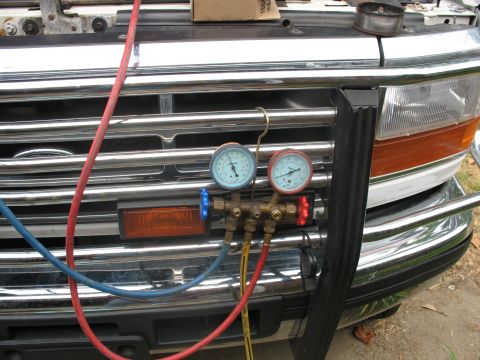 1995 Ford C-350 (Centurion Conversions) - AC manifold gauge set connected to the front of a 1995 Ford truck, likely for servicing the air conditioning system.