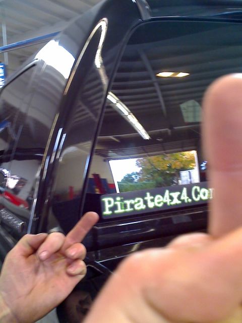 1971 Ford Bronco - A sticker on the rear window of a vehicle displays a website address, with a hand giving the middle finger in the foreground.