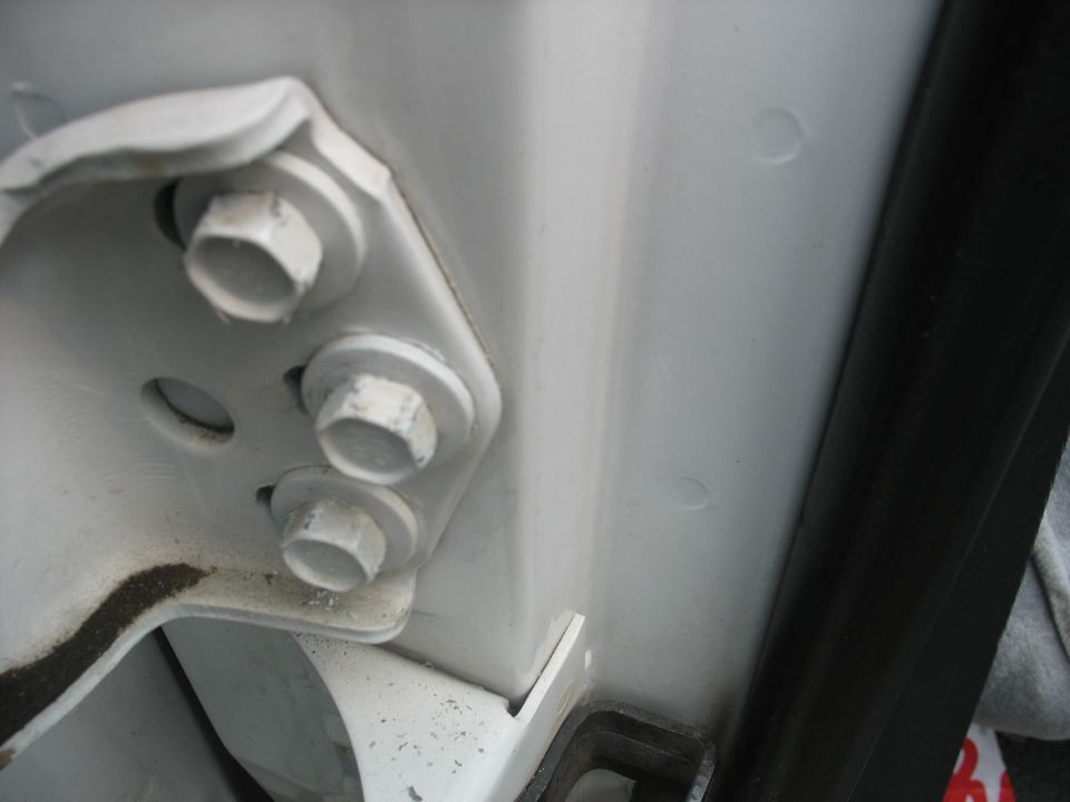 White door hinge bolts on a vehicle