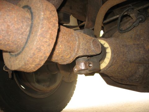1995 Ford C-350 (Centurion Conversions) - Close-up view of the driveshaft and differential assembly on a heavily rusted vehicle.