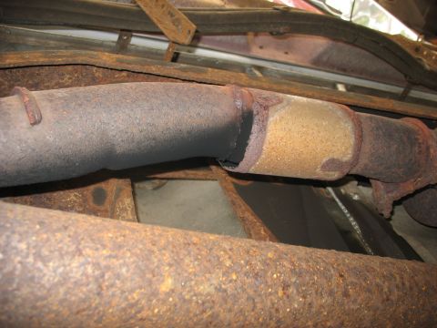 1995 Ford C-350 (Centurion Conversions) - Rusted exhaust system components, including a catalytic converter, are visible from underneath.