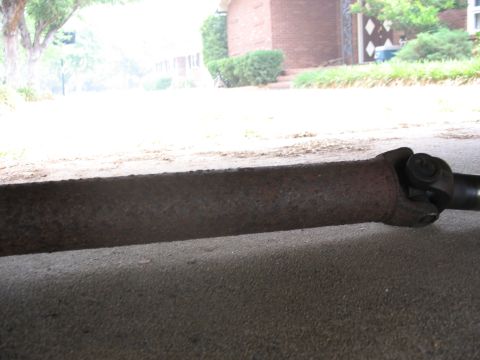 1995 Ford C-350 (Centurion Conversions) - Close-up view of a rusty driveshaft and U-joint, likely from under a vehicle.
