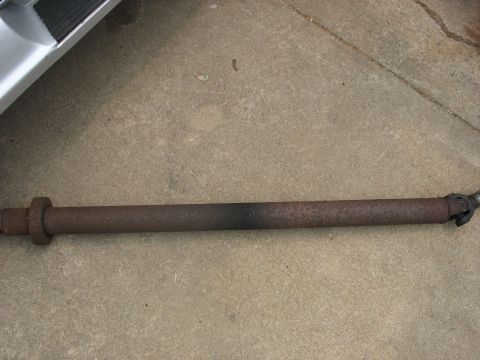 1995 Ford C-350 (Centurion Conversions) - Driveshaft shown resting on concrete, with part of a vehicle body in the upper left corner.