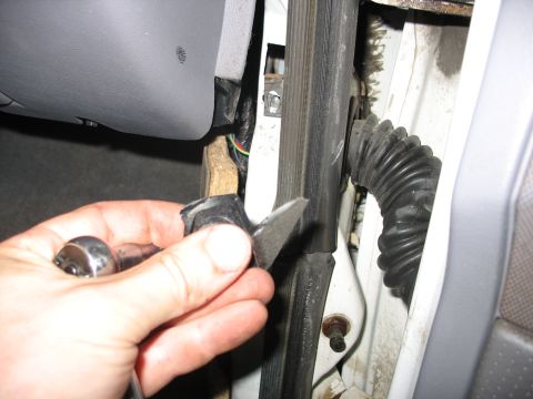 1995 Ford C-350 (Centurion Conversions) - Close-up of a hand using a utility knife and socket wrench to repair the interior door jamb of a vehicle.