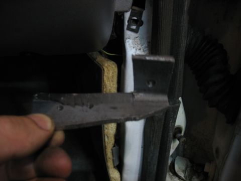 1995 Ford C-350 (Centurion Conversions) - A hand holds a broken metal door hinge, showing damage to the vehicle's door frame.