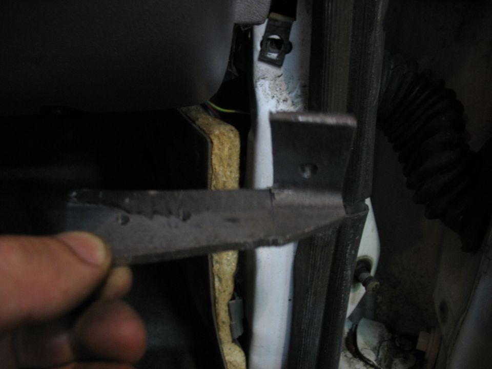 Close-up of a damaged door hinge being held by a hand