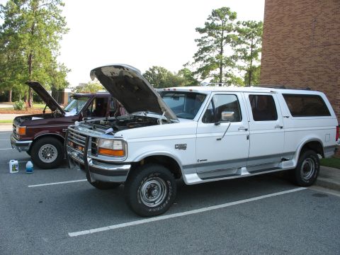 1995 Ford C-350 (Centurion Conversions) - Two Ford vans, a white C-350 and a maroon model, sit with their hoods open in a parking lot.