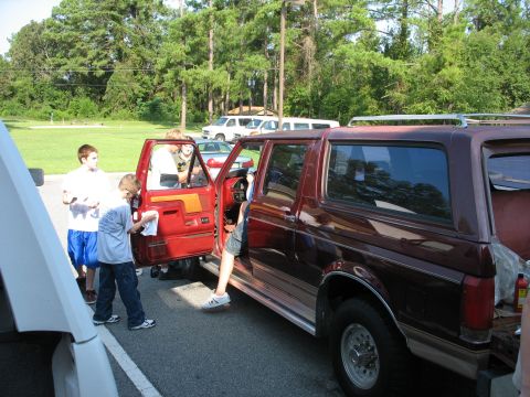 1995 Ford C-350 (Centurion Conversions) - A group of people are gathered around a maroon 1995 Ford C-350 Centurion Conversions SUV with its doors open.
