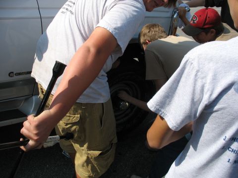 1995 Ford C-350 (Centurion Conversions) - Group of people changing a tire on a vehicle, possibly a van or truck.