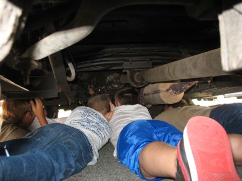 1995 Ford C-350 (Centurion Conversions) - Boys examine the underside of a vehicle during a training session.