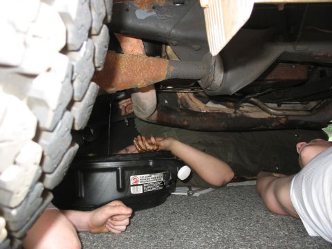 1995 Ford C-350 (Centurion Conversions) - Two individuals are seen working on the underside of a vehicle, performing an oil change.