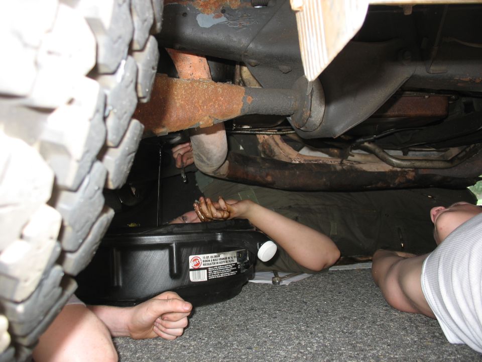 Underside view of a vehicle with people changing the oil