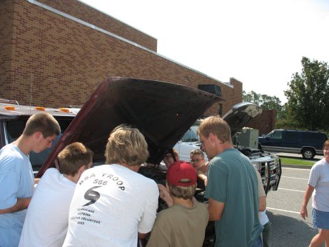 1995 Ford C-350 (Centurion Conversions) - Group of young men examine the engine of a maroon Ford F-Series truck.