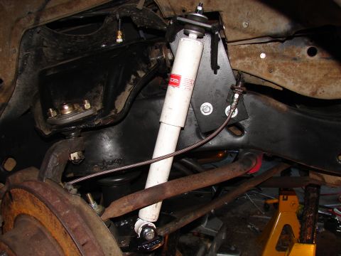 1973 Ford Ranchero - Underbody view of a front suspension mid-rebuild, showing a white KYB Gas-a-Just shock absorber mounted between freshly painted black contr…