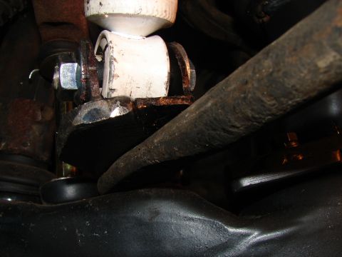 1973 Ford Ranchero - Tight close-up under a vehicle showing a white polyurethane bushing seated in a rusty bracket with a fresh zinc-plated bolt and washer, alo…