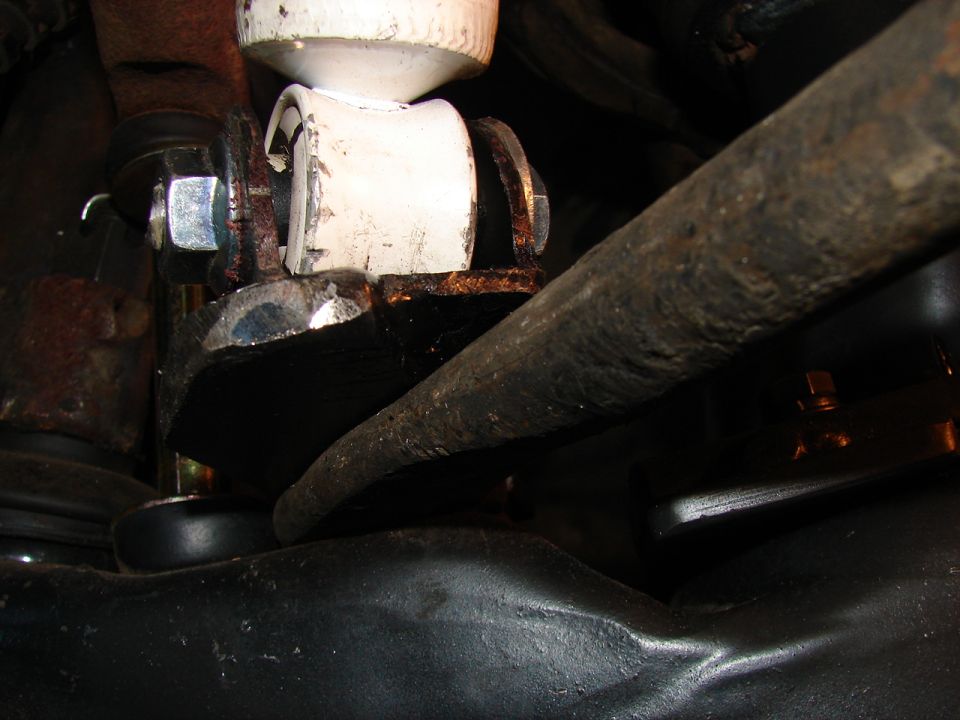 White polyurethane bushing in a rusty bracket with new plated bolt under a vehicle