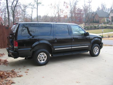 2005 Ford Excursion - Black 2005 Ford Excursion SUV parked on a driveway with houses in the background.