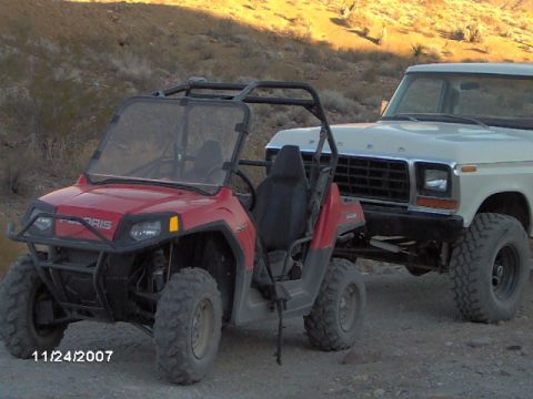 1979 Ford Bronco - A white Ford truck, identifiable by its 1979 grille, is parked alongside a red Polaris UTV in a desert landscape.