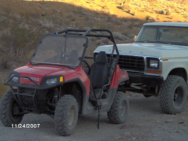 White Ford truck with a 1979 grille, parked next to a red Polaris UTV