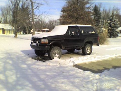 1995 Ford Bronco - A black Ford Bronco sits in a snowy landscape under a clear blue sky.