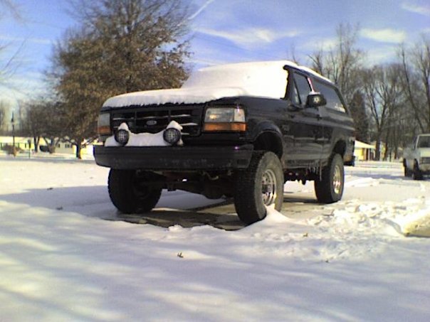 Snow-covered lifted black Bronco SUV in a snowy lot