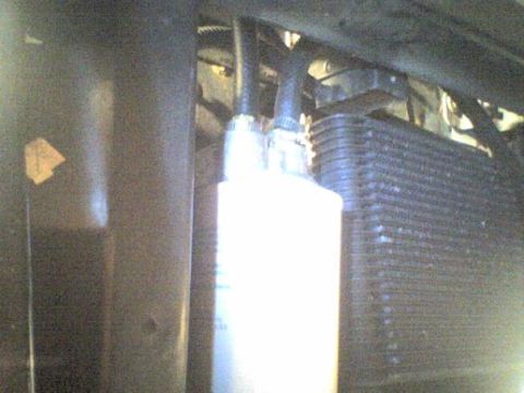1995 Ford Bronco - Close-up view of an engine oil cooler and filter assembly with attached hoses.