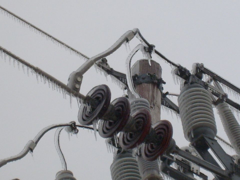 Power lines and insulators coated in ice with icicles hanging down