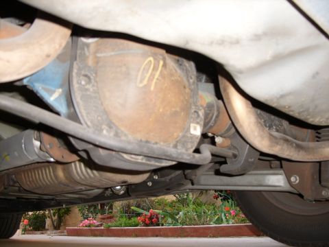 2005 Ford Crown Victoria - The underside of a vehicle shows a rusty rear differential and exhaust system components.