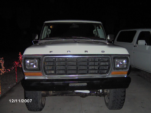 Front view of a 1979 Ford F-150 truck, with another white truck partially visible to the right